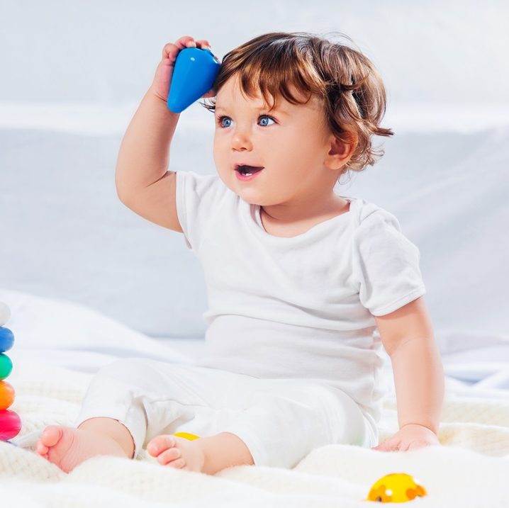 Happy baby boy sitting with toy